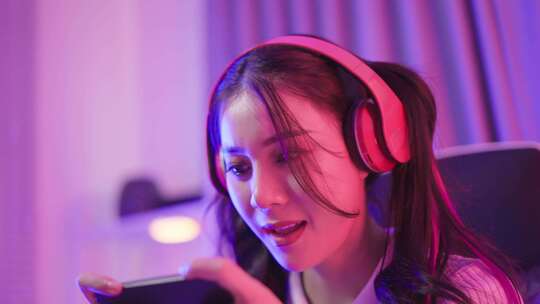 亚洲美丽的电子竞技女玩家在电脑上玩在线手机游戏。