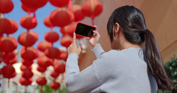 女人用手机拍红灯笼照片