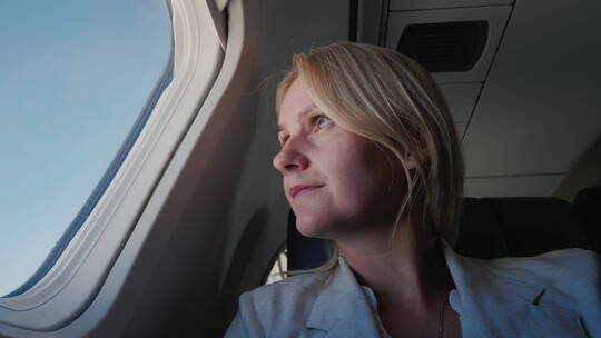 一个女乘客坐在飞机上向窗外望去的肖像