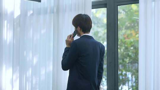 商务男子窗边打电话办公
