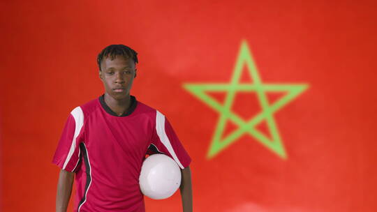 在摩洛哥国旗前抱着足球的运动员