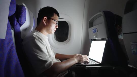 中年男子在飞机上使用笔记本电脑工作