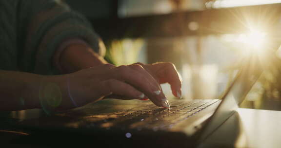一个中年女人的手正在笔记本电脑键盘上输入文本
