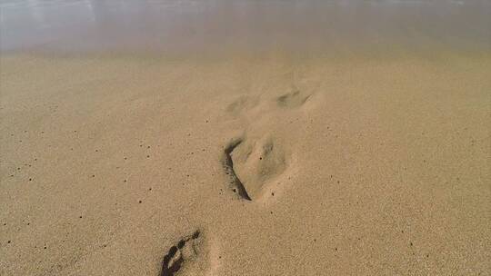 海浪冲刷沙滩上的脚印