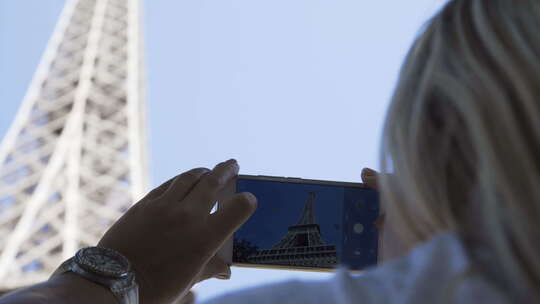 女人用手机拍摄埃菲尔铁塔