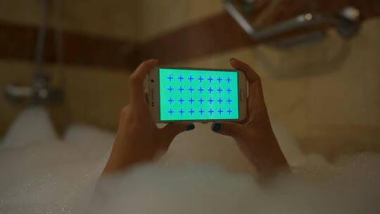 泡沫浴中拿着手机的人