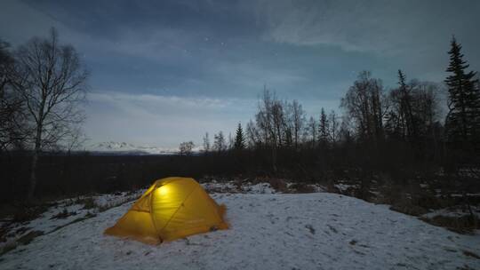 夜里明亮的黄色帐篷和雪景