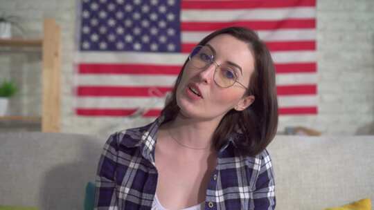 美国国旗背景上穿着衬衫的年轻女性博客作者录制视频特写