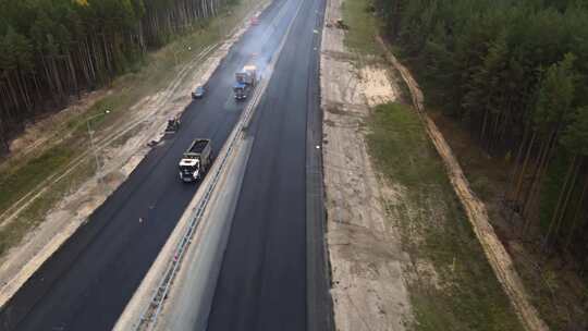 道路机械在修理高速公路。沥青自卸车缓慢行驶