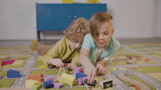 两个小朋友趴在地板上玩积木视频素材模板下载