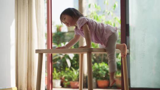 顽皮的亚洲小女孩在家里玩耍爬上桌子跳舞