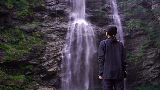 女性游客背影面向山水感受亲近自然山峰瀑布