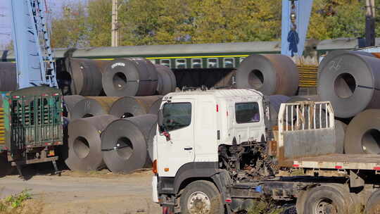钢材厂内货车旁堆放钢卷的场景