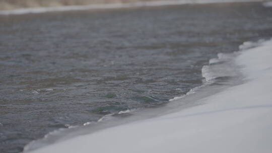 流水拍打结冰的河岸4k50帧灰片
