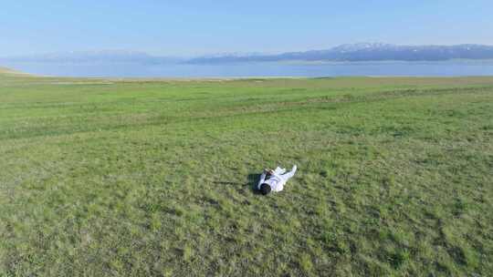 航拍男子躺在夏天赛里木湖畔的草地上