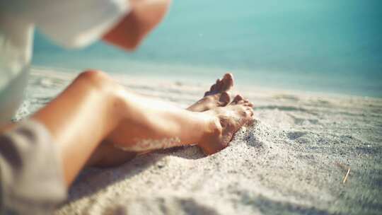 女人坐在海滩上晒日光浴视频素材模板下载