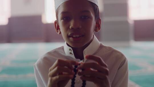 穆斯林男孩开心的玩串珠