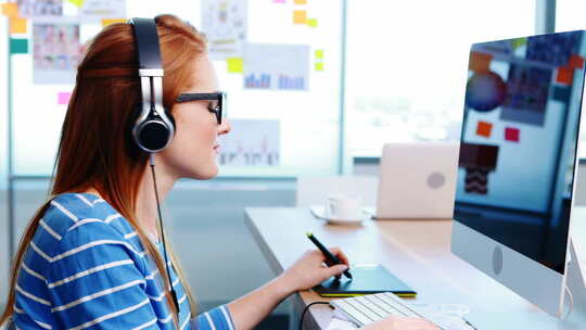 女性平面设计师一边在办公桌前听音乐一边工