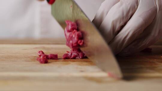 厨师用刀将肉切成肉粒