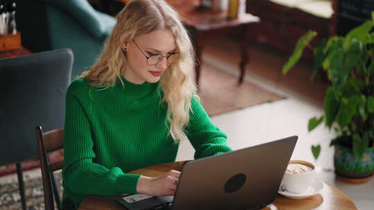 在咖啡屋使用笔记本电脑工作的女性在工作或友好聊天中输入消息肖像视频素材模板下载