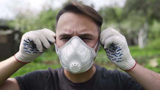 戴工作手套的人在户外戴上呼吸器，对人体的
