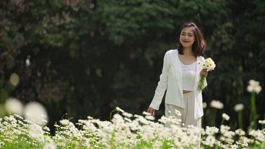 女青年拿着一束鲜花在春天草地散步慢镜头
