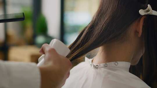 美发师用美容产品喷洒头发的手持式视图