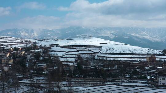 冬季阳光晴天白雪覆盖田野农村远处连绵雪山