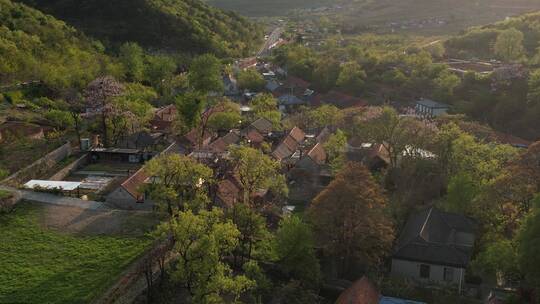 航拍横移俯瞰春天山野中的山谷村庄视频素材模板下载