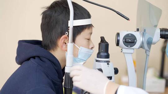 男孩医院诊所检查仪器前做眼科视力检查