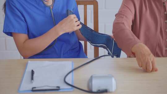 亚洲护理医生检查老年患者使用血压计。视频素材模板下载