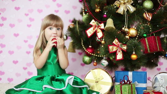 女孩坐在圣诞树旁吃苹果