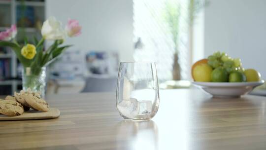 在厨房的桌子上往玻璃杯里倒一杯苏打水