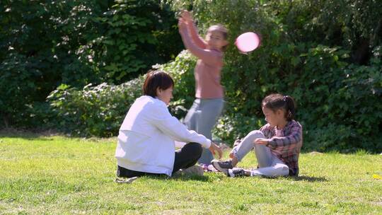 秋天午后围坐在草坪上玩耍的母亲和女孩