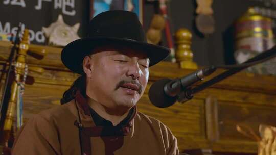 男子戴帽对着麦克风演唱