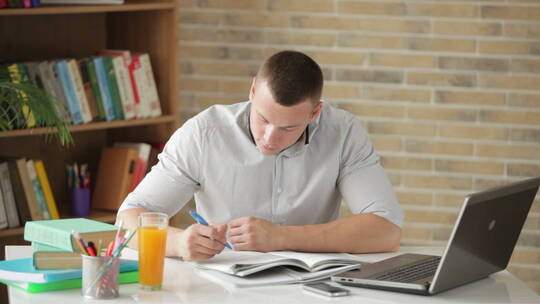 男人坐在桌旁用笔记本电脑学习