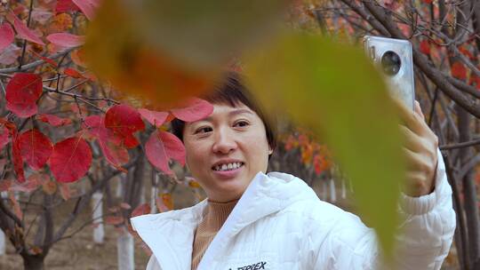 秋天在枫树林手机自拍直播的东方年轻女性