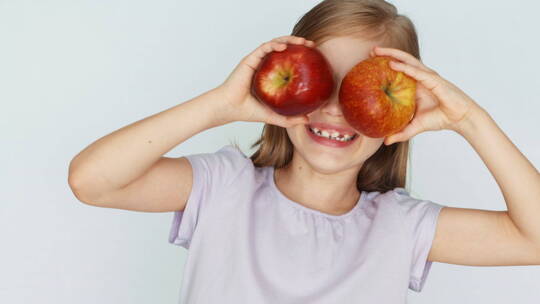 小女孩用两个苹果挡住眼睛