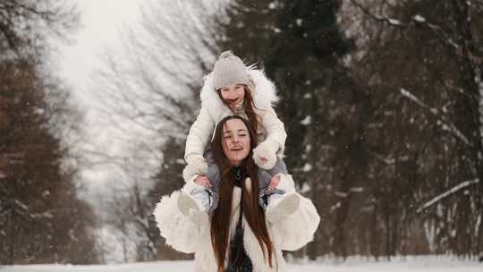 一个女人在雪地里扛着一个女孩