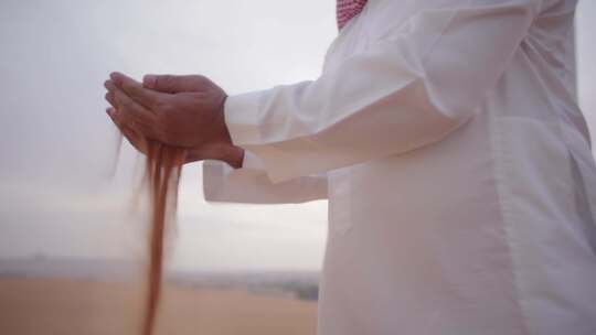 沙特人沙漠捧起沙子飘散在手中视频素材模板下载