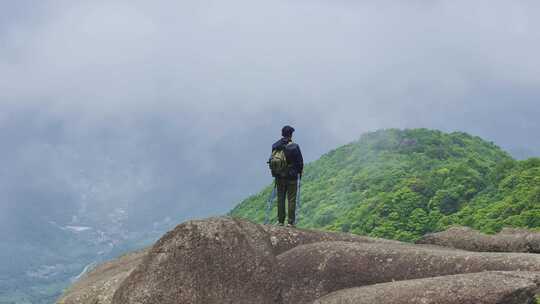 男子山顶持杖眺望山间景色