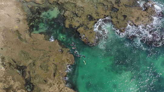 绿松石海水中浮潜游客上空的空中升起，岩石海岸