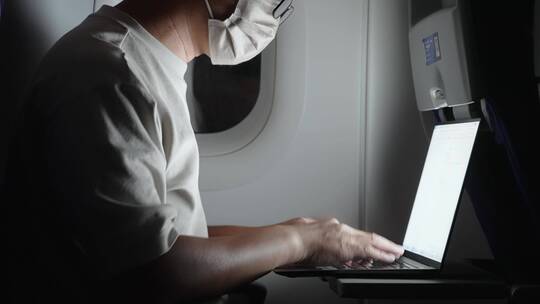 疫情期间男子在飞机上使用笔记本电脑