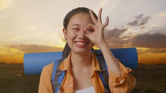 亚洲女性徒步旅行者在山顶上用手指遮住眼睛