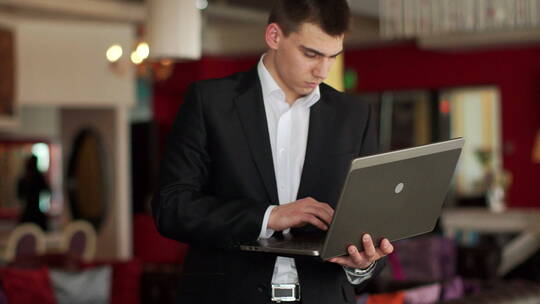 一个人站在咖啡馆里拿着笔记本电脑打字