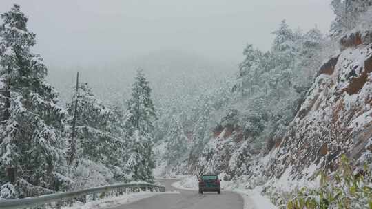 雪天山林间的蜿蜒公路与驶过的汽车