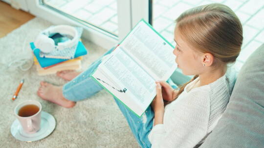 女孩做在地毯上读书