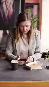 女人一边用手机一边吃早餐