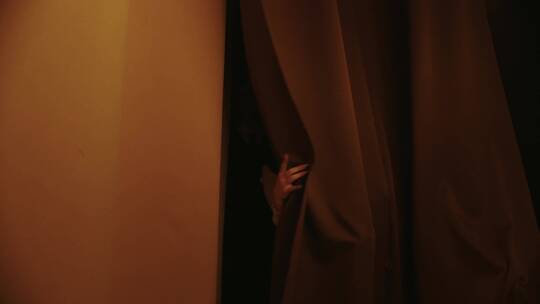 女生在舞台后面在拉开窗帘
