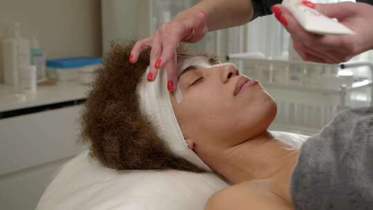 专业美容师在水疗沙龙为黑人女性客户涂抹面